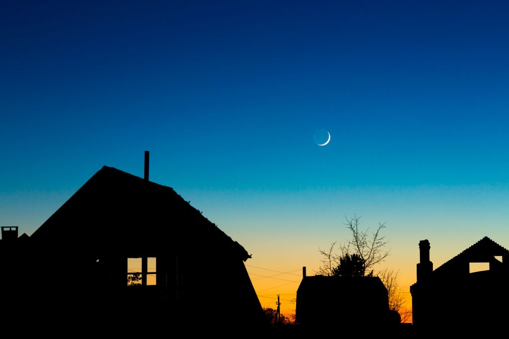 Houses roofs against the night sky with new moon